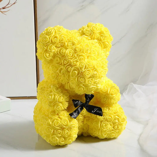 a yellow teddy bear sitting on a white surface 