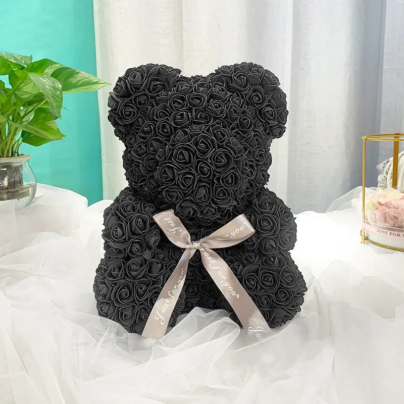 a black teddy bear sitting on top of a bed 