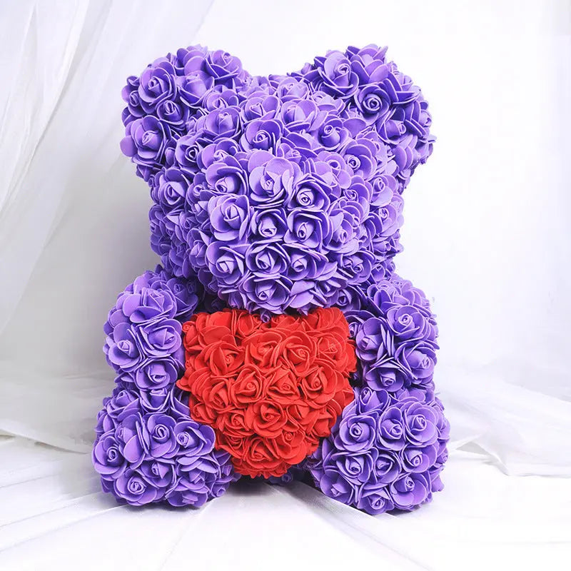 a purple teddy bear sitting on a bed 