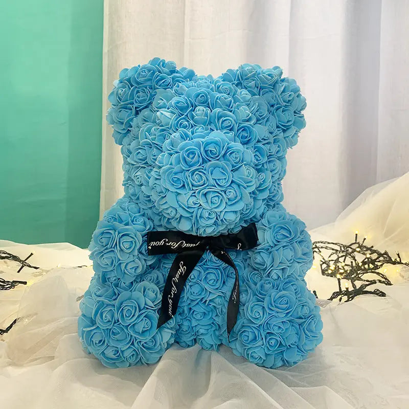 a blue teddy bear sitting on top of a bed 